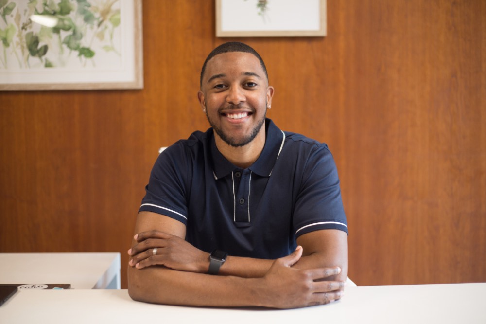 Smiling man in a navy polo shirt at his desk